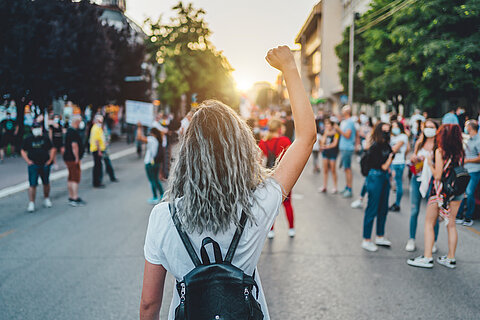 Person mit erhobener Faust protestiert auf der Straße